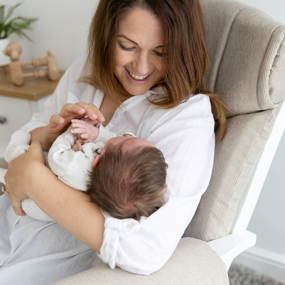 Parent cuddling baby in the Chatsworth nursing glider chair